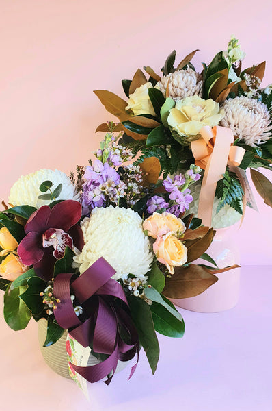 A beautiful ceramic pot arrangement made with lush foliages and beautiful blooms and a ribbon to match